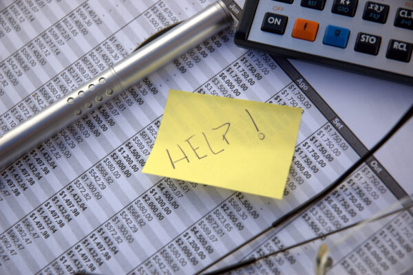 Help on a sticky note on top of paperwork with numbers on it