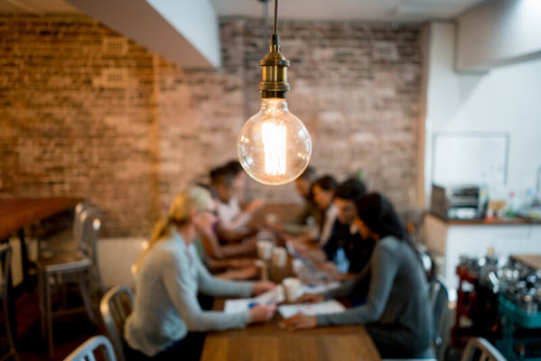 A team having a meeting under a lit lightbulb.