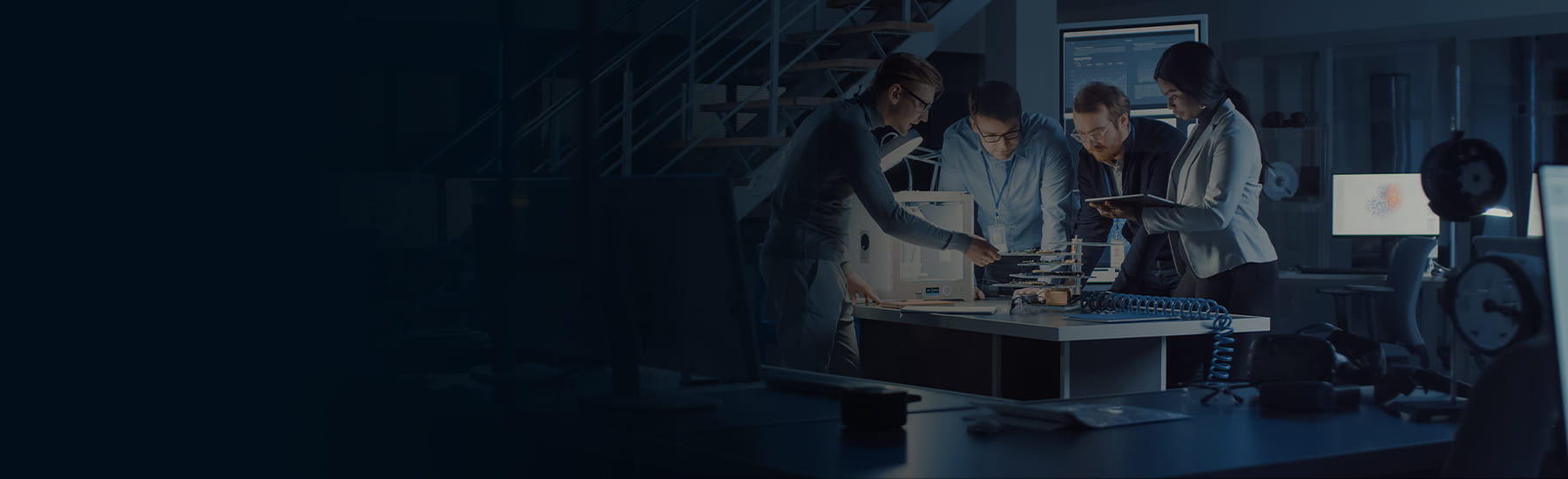 A group of people in a lab standing around a table working on something 