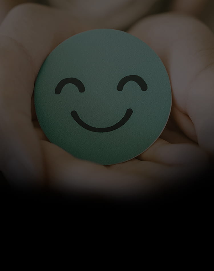 A hand holding a blue smiley face