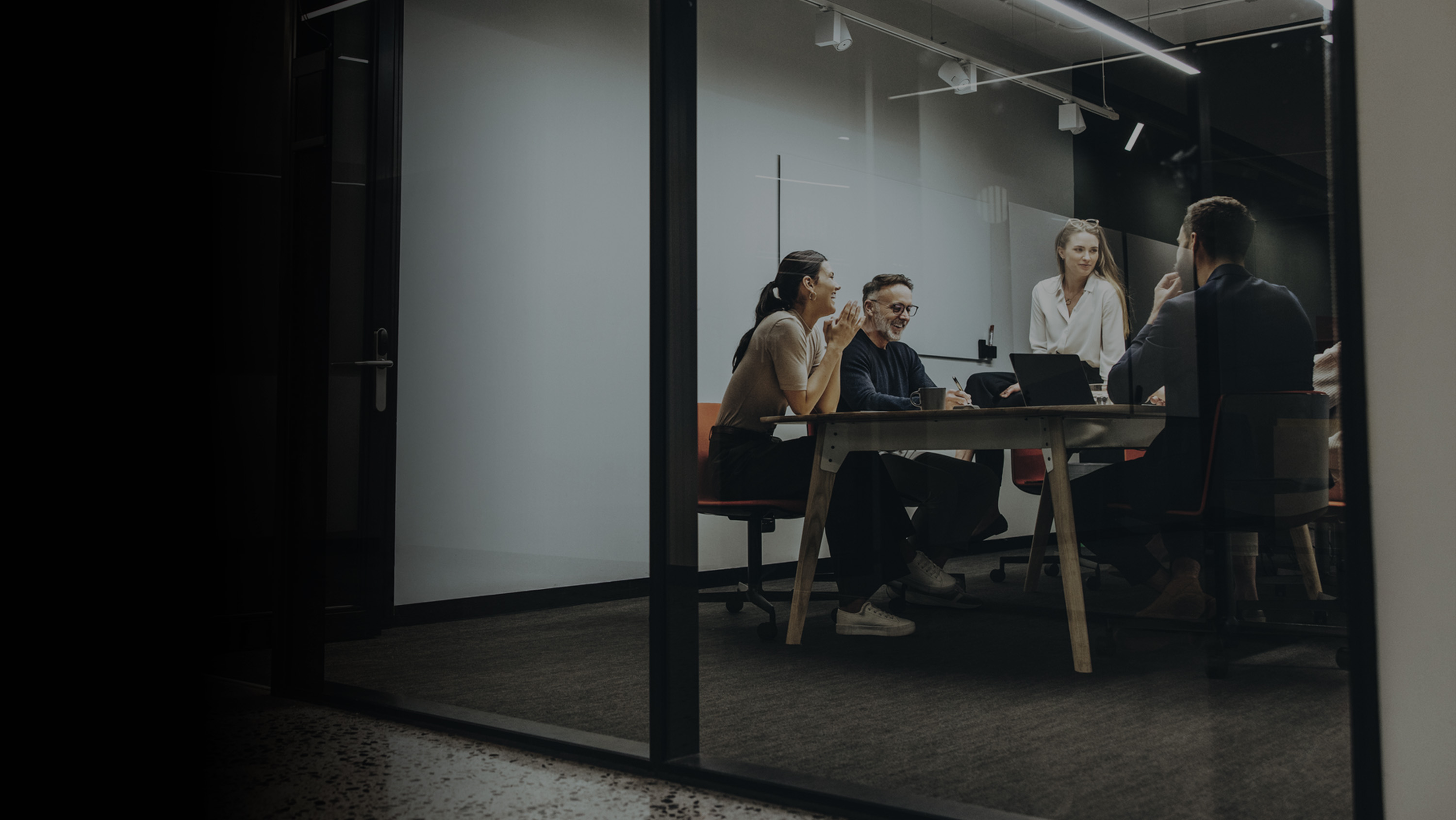 Gradient image of several colleagues sitting around a table in a conference table.