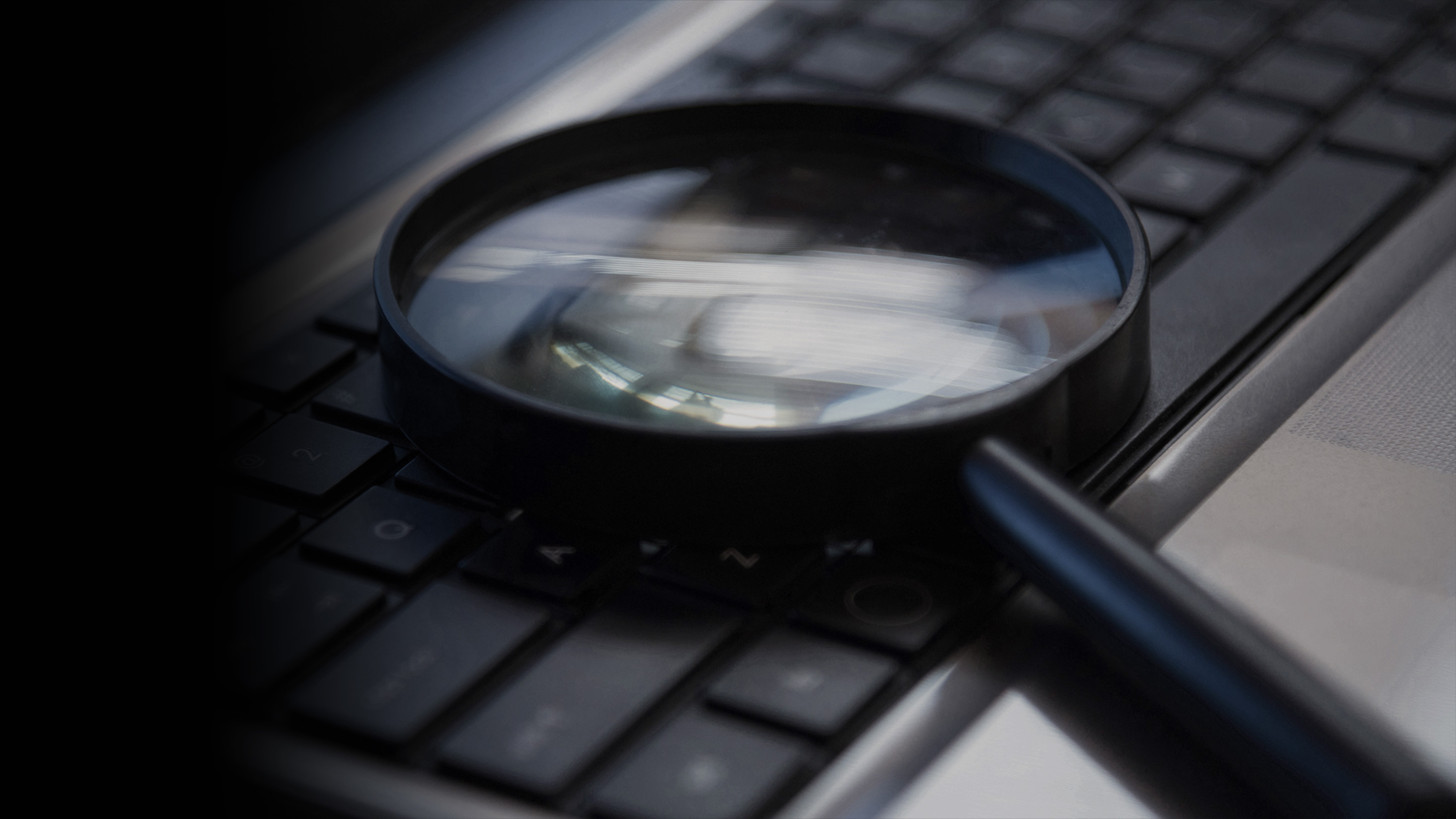 A magnifying glass sitting on top of a computer keyboard.