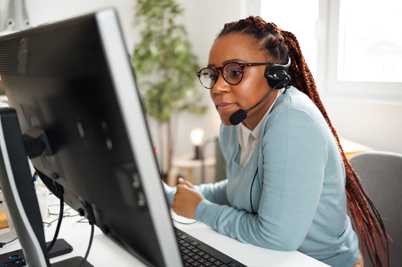 Woman Wearing Microphone Headset Staring at Desktop Computer