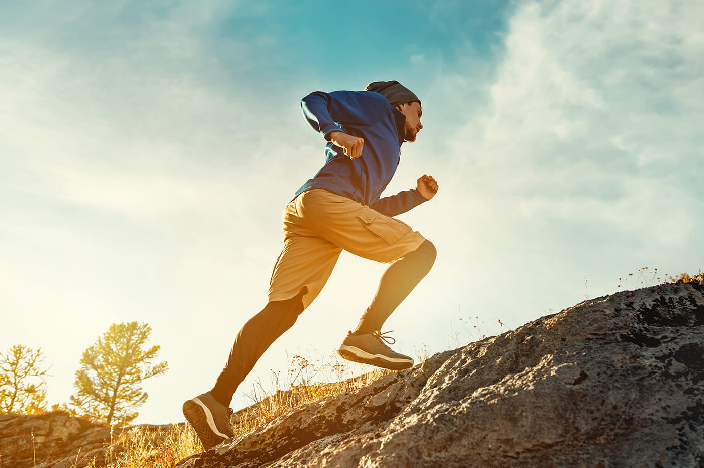 A man running up a rocky hill in the sunset.