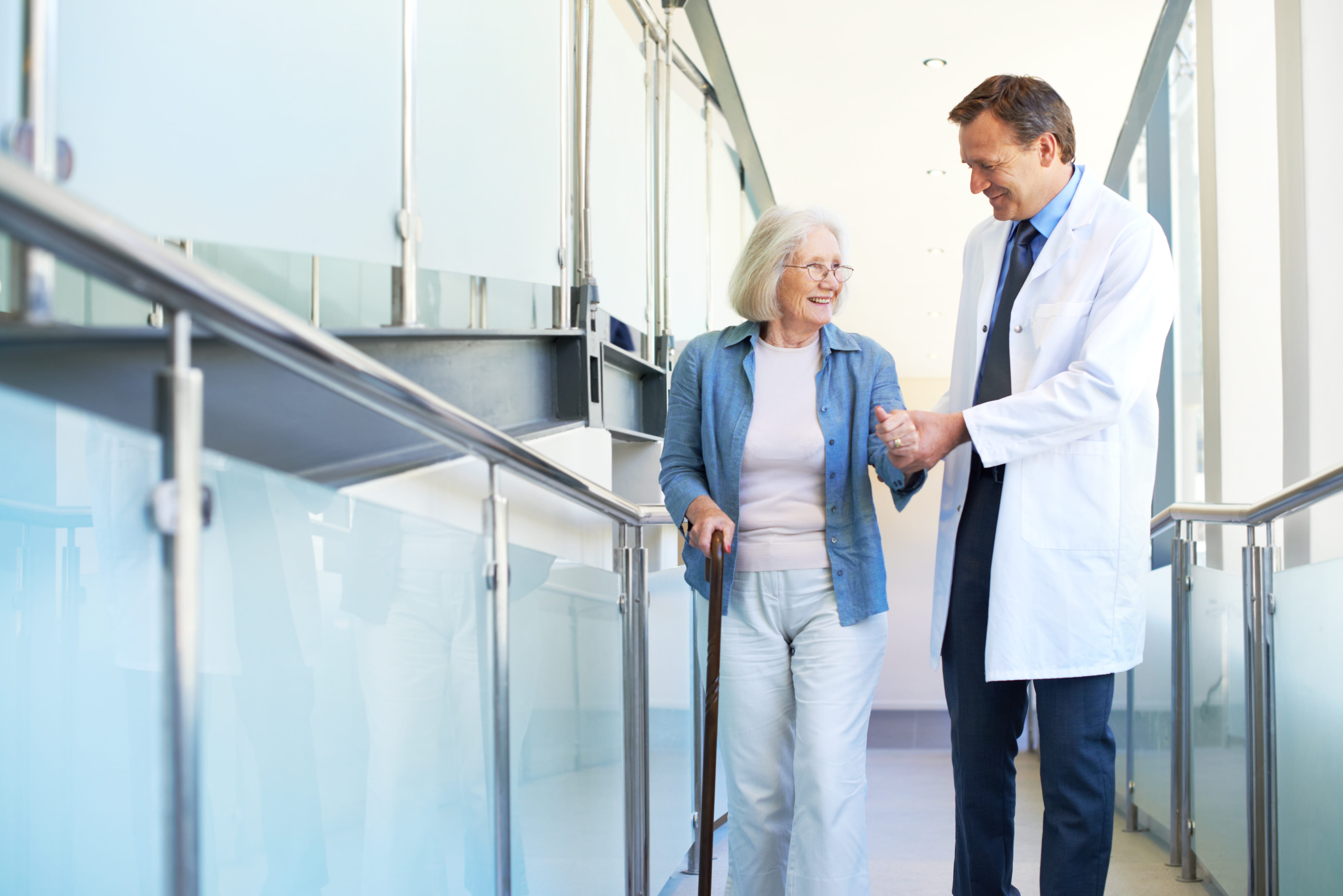 A doctor helping an elderly patient walk.