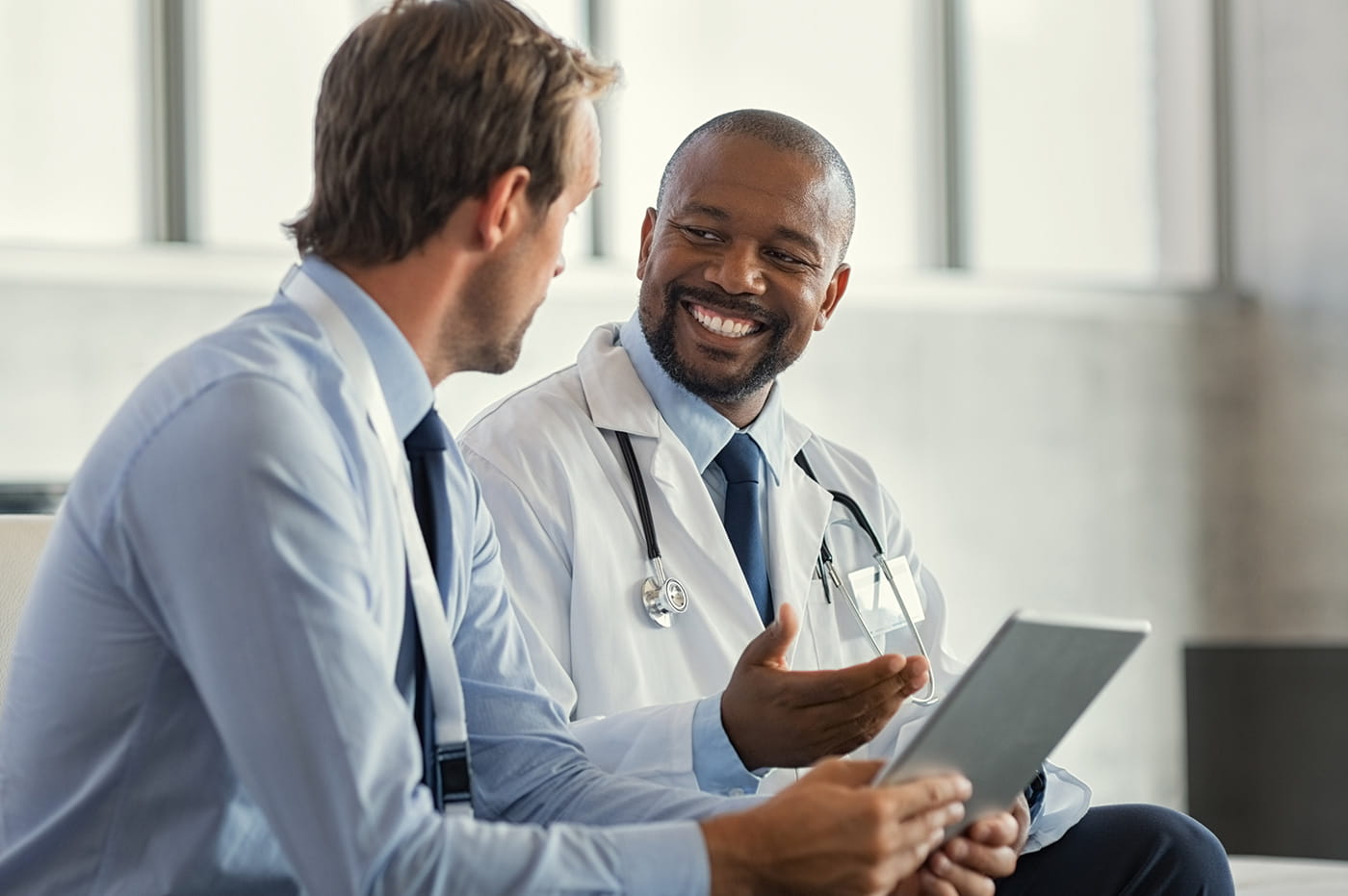 Two healthcare workers talking and looking at a tablet.