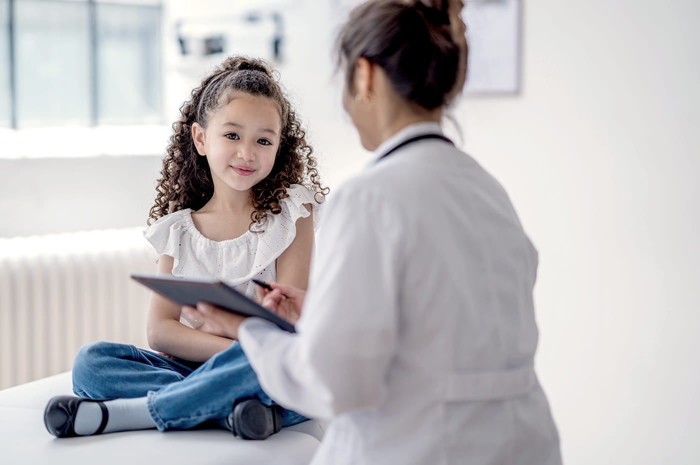 A doctor using a tablet to explain something to a little girl.