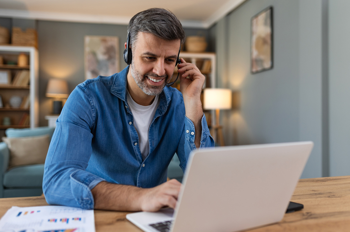 Man shopping on a laptop and talking on the phone.