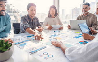 Coworkers in a meeting looking at paperwork on a table