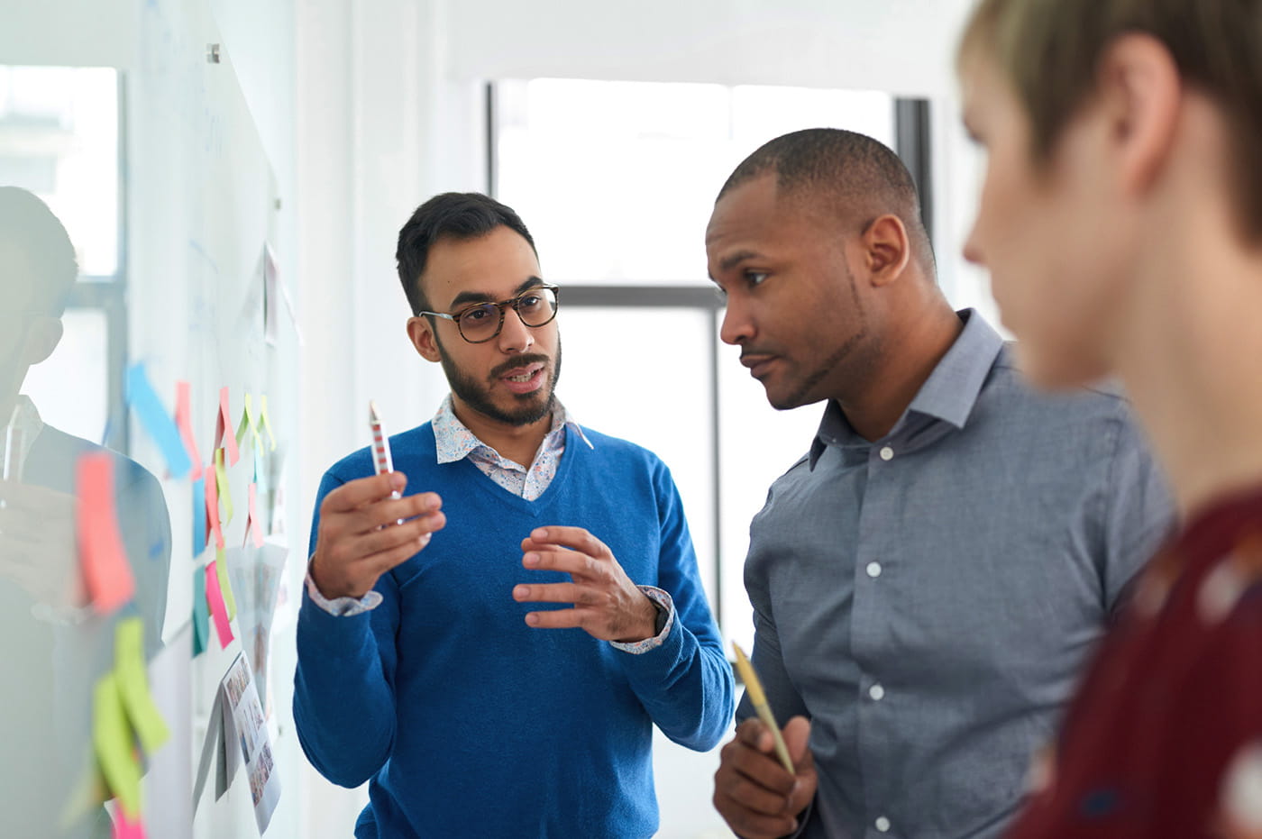 3 male coworkers standing in front of a whiteboard with sticky notes