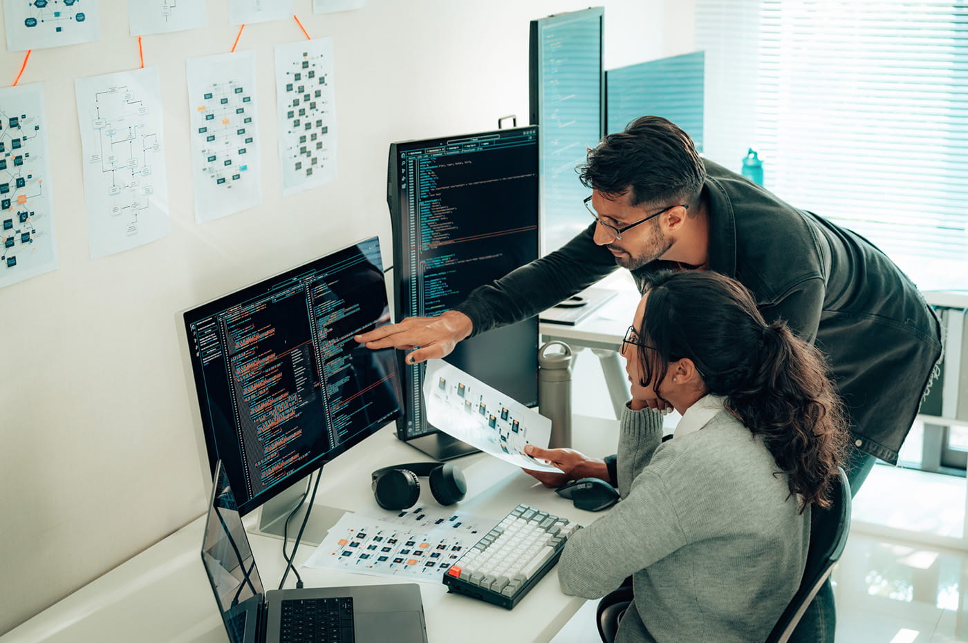 Coworkers working on something and a coworker pointing at a computer screen