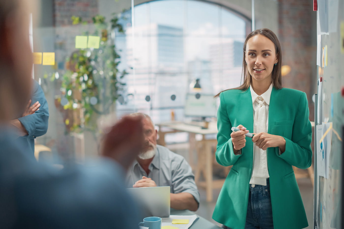 A woman in a green jacket looking at another person 