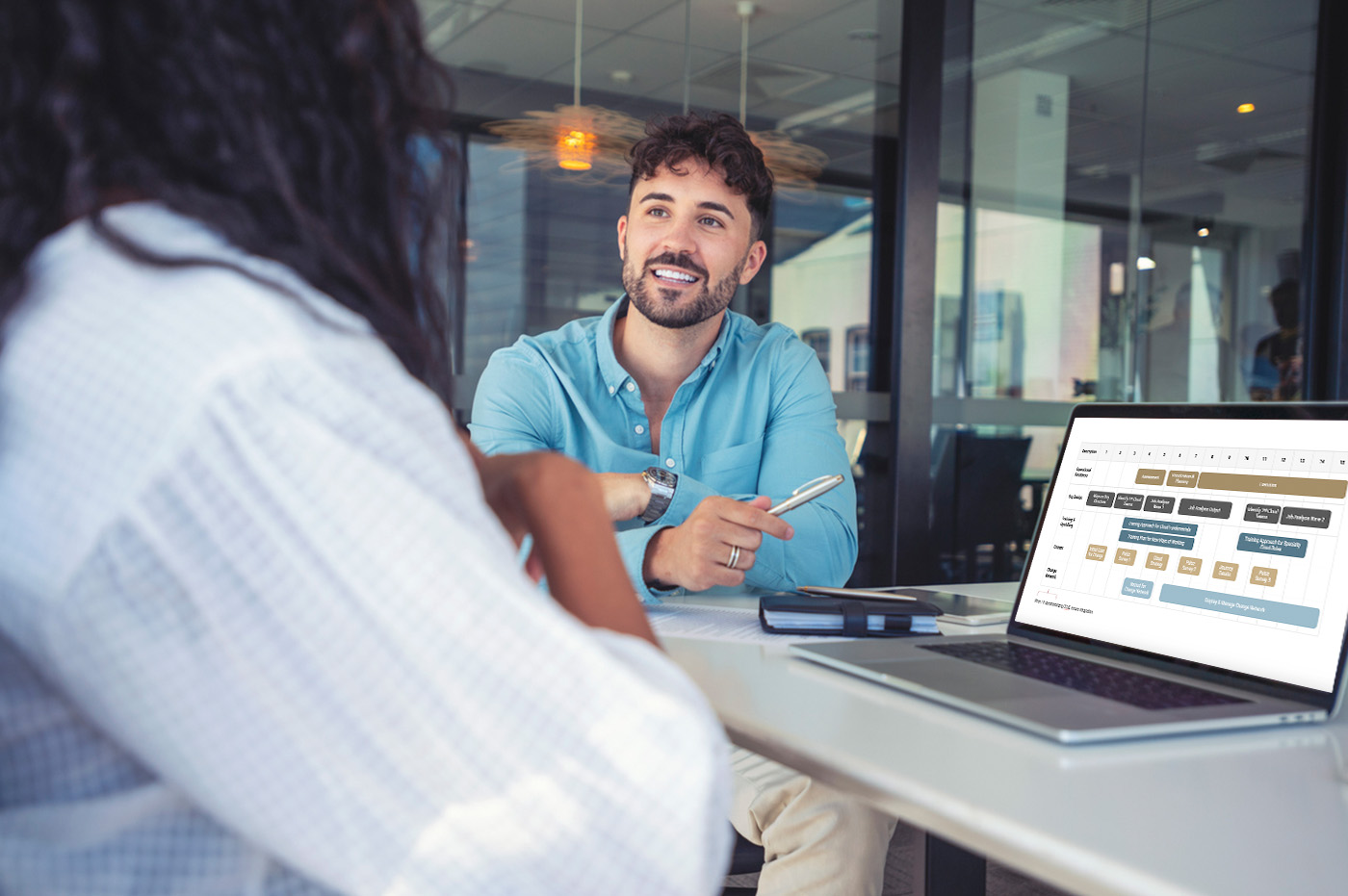 A man sitting next to a woman going over a timeline on a laptop screen