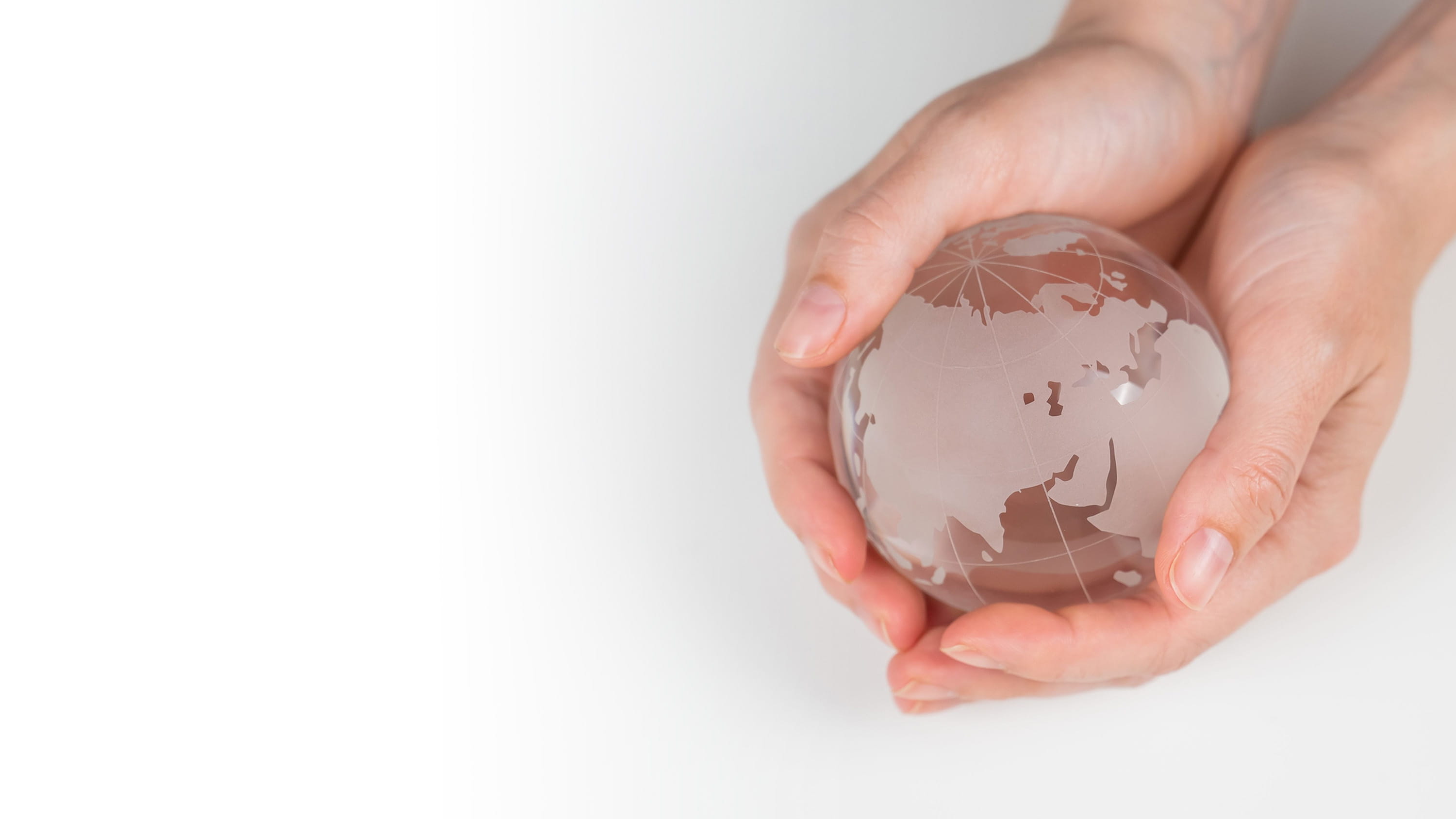 Two hands holding a glass globe.