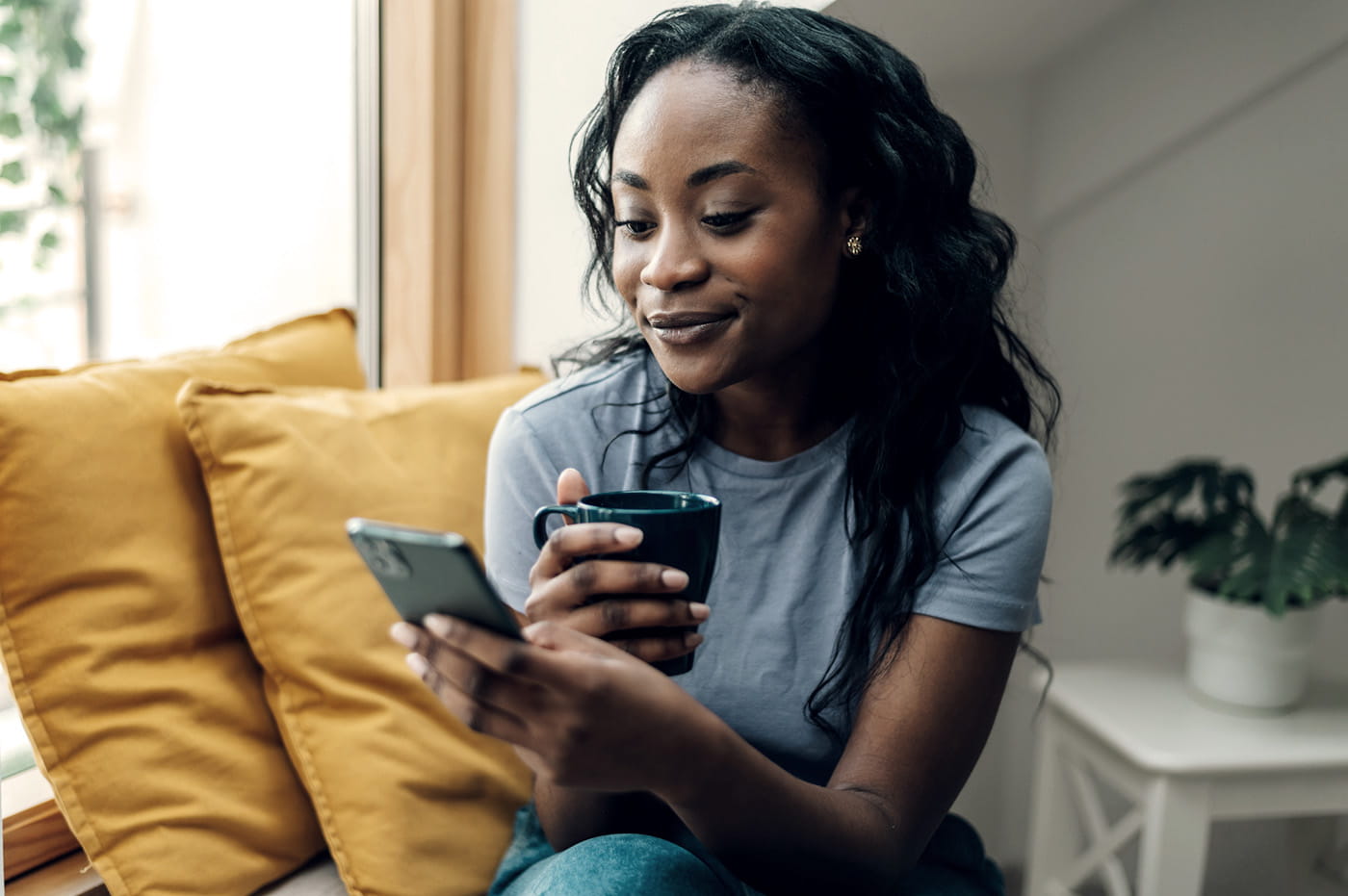 A woman sitting on the couch looking at her smartphone. 