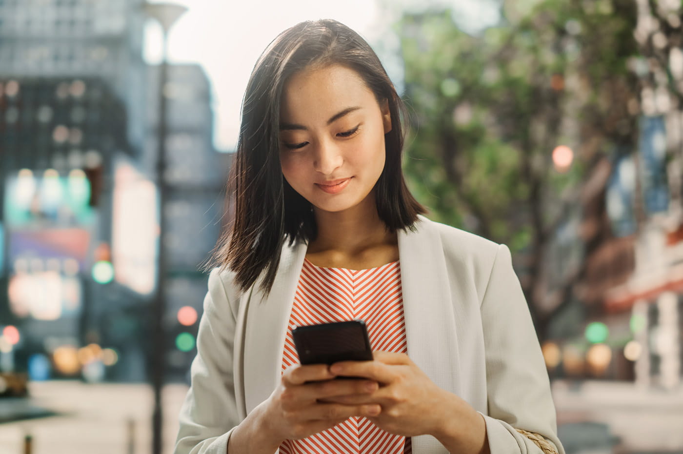 Woman looking at her mobile phone while walking down the street.