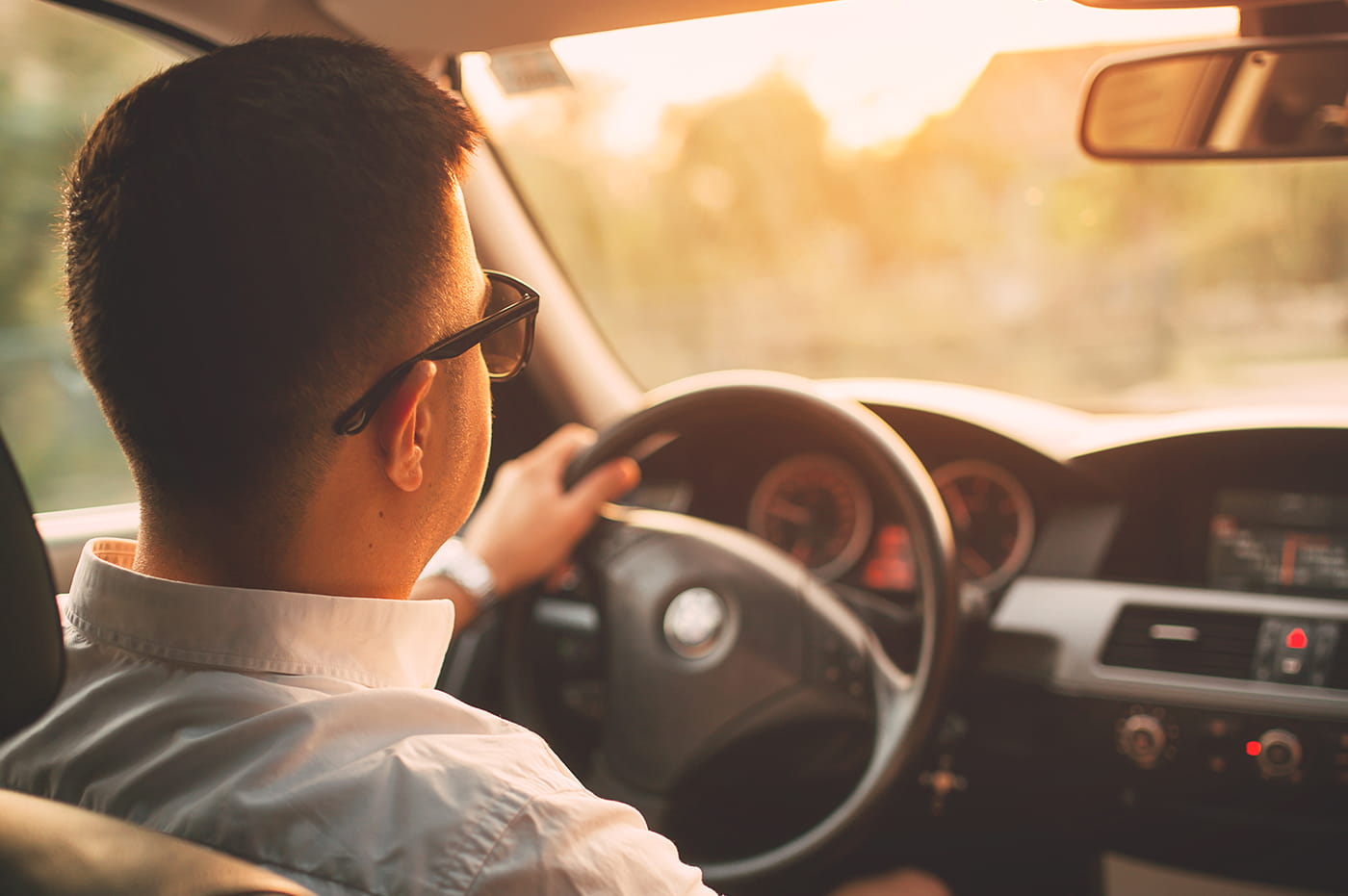 Man in car driving in the sunset (card image).